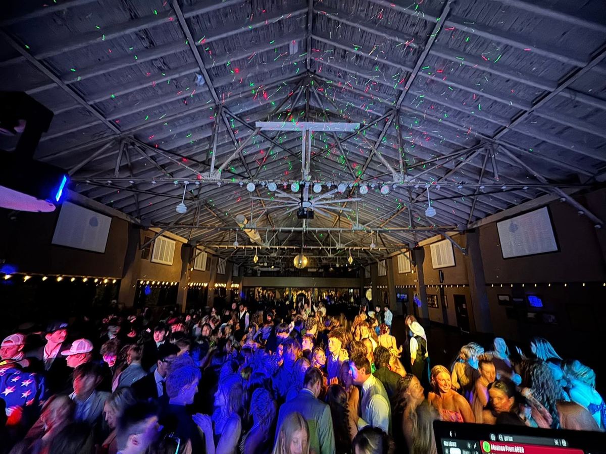 A packed prom dance floor under laser lights